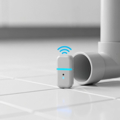 Modern smart home water leak sensor on a floor next to a pipe