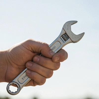 Hand holding a wrench, symbolizing proactive plumbing maintenance and prevention